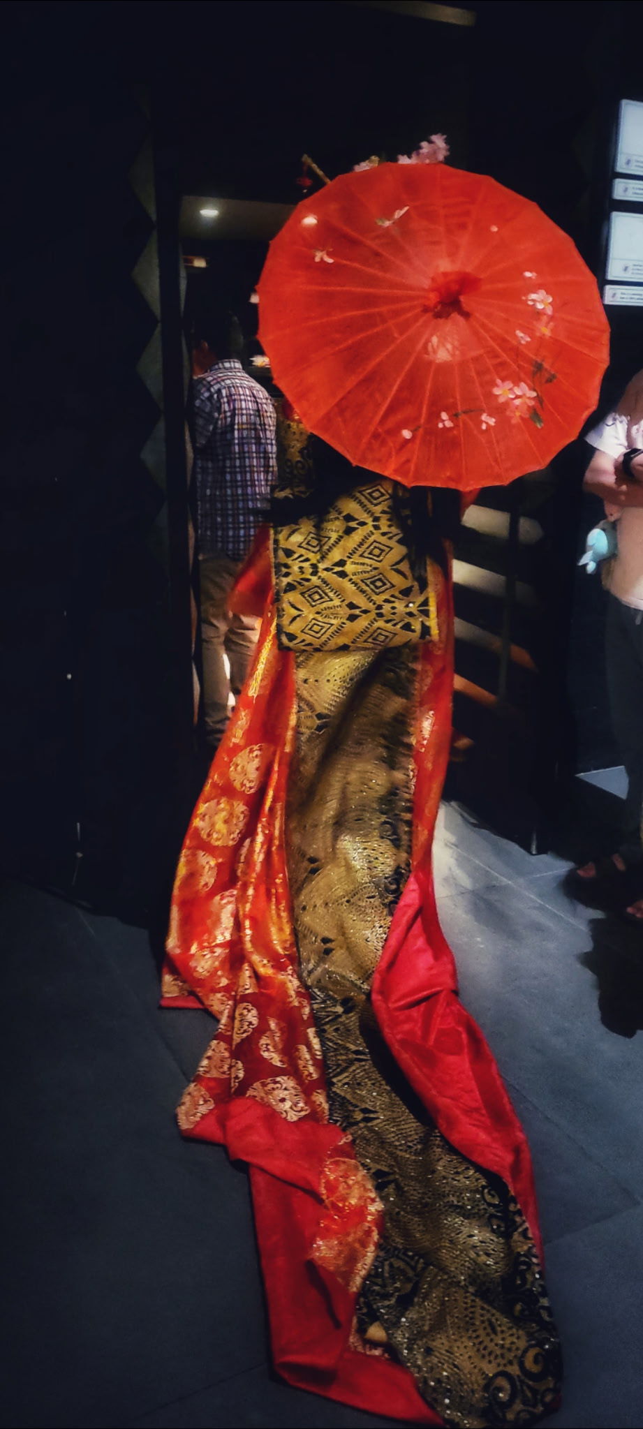 a geisha holding a parasol with her back turned